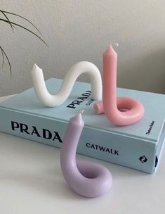 a pink candle sitting on top of a blue book next to a white and pink snake