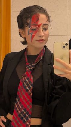 a woman with face paint taking a selfie in front of a mirror while wearing a tie