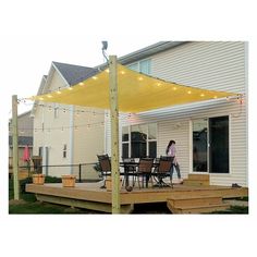 a woman is walking on the back deck of a house with an awning over it