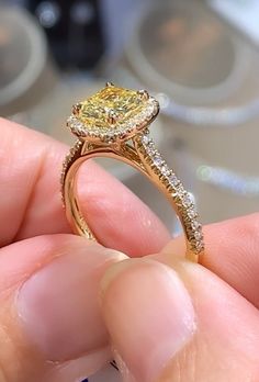 a person holding a yellow diamond ring in their hand