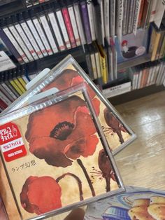 a person holding three cds in front of a book shelf