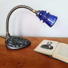 an open book sitting on top of a wooden table next to a blue light fixture