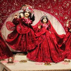 three dolls dressed in red sitting on a table