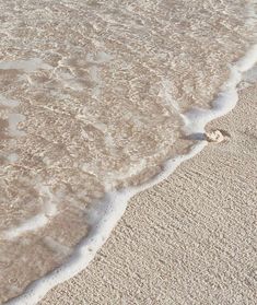 a person walking on the beach with their surfboard in hand and footprints in the sand