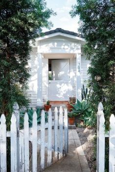 a white picket fence is in front of a small house