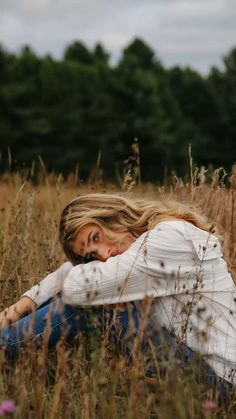 a woman is sitting in the middle of tall grass