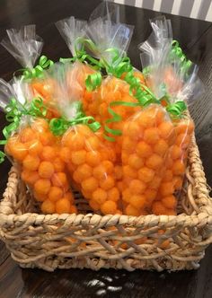 some carrots wrapped in plastic sitting on a table next to a basket with green ribbon