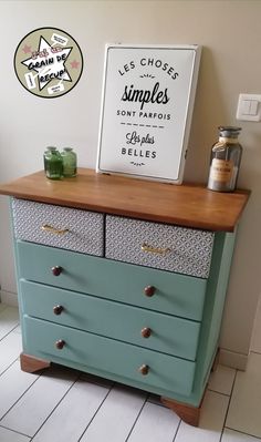 a blue dresser with drawers and a sign above it that says les chosers simples