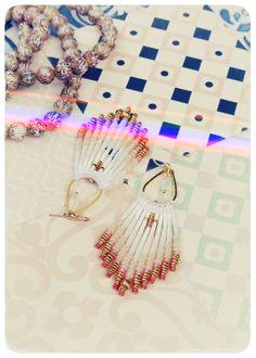 two pairs of beaded earrings sitting on top of a table next to some beads