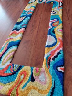 a multicolored rug is laying on the floor in front of a wooden floor