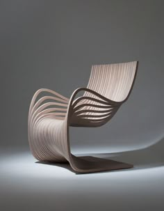 a wooden chair sitting on top of a white floor next to a gray wall with light coming through it