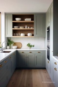 a kitchen with gray cabinets and white counter tops, wood floors, and wooden flooring