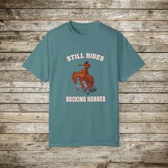 Check out my funny new wild west rodeo cowboy graphic T-Shirt, Done in the Retro Style of the 80s and 90's, this graphic western shirt, pokes gentle fun at the manly and bravery it takes to ride a bucking bronc horse. Every now and then you have to step back and say wow! Look at that guy ride! and wonder... How many rocking horse the went through as a toddler... ☺️??? Gotta love a cowboy! This super comfy comfort color tee has a relaxed fit and the cotton is soft and durable. This will make a great gift for the guy with a sense of humor! Comfort Colors Tshirts: About the Designer of FlooredByArt Studios: ☀️As an artist I try to capture the beauty of nature and the spirit of beloved animals with these stunning archival quality prints. Each design is crafted using cutting-edge digital artist Western Style Relaxed Fit Graphic T-shirt, Western Style Relaxed Fit T-shirt With Graphic Print, Western Style Crew Neck T-shirt With Graphic Print, Western Style Relaxed Fit T-shirt With Screen Print, Short Sleeve T-shirt With Letter Print For Western-themed Events, Western Style Cotton Graphic T-shirt, Western Style Cotton T-shirt With Graphic Print, Retro Western Style Short Sleeve Top, Western Style Screen Print T-shirt For Western-themed Events