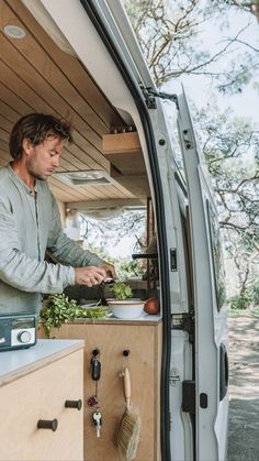 a man cooking food in the back of a van