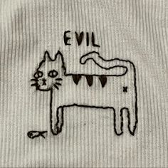 an embroidered shirt with a cat on it's chest and the words evil written in black ink