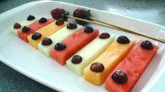 there are many slices of watermelon and other fruits on the plate with chopsticks