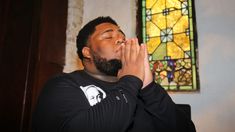 a man is praying in front of a stained glass window