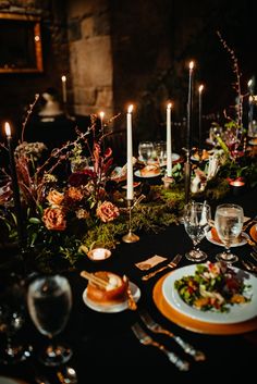 a dinner table with candles and flowers on it is set for an elegant event or celebration