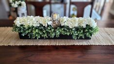 the centerpiece is made up of flowers and greenery on top of a table