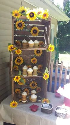 sunflowers and cupcakes are arranged on an old wooden crate for display