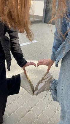 two women standing on the sidewalk touching their hands with each other's fingertipss