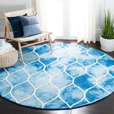 a blue and white area rug in a living room with a chair, potted plant and window