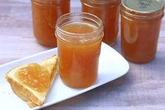 several jars of honey sit on a plate next to a slice of bread and jam