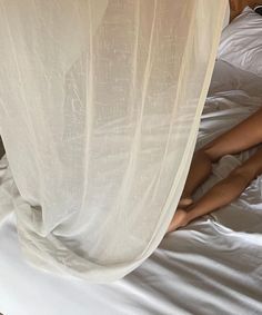 a woman laying on top of a bed next to a white canopy over her head