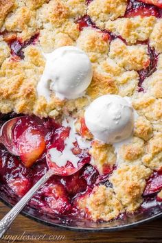 a skillet filled with fresh fruit and ice cream on top of a wooden table