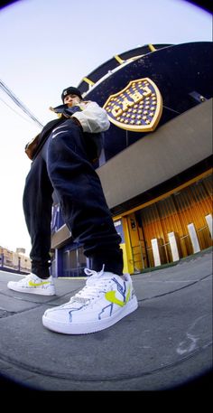 a man standing on top of a skateboard next to a tall building with a yellow and blue logo