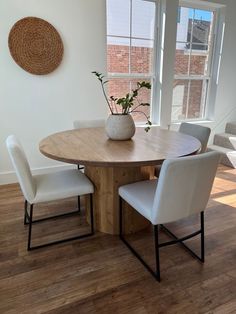 a wooden table with white chairs and a potted plant sitting on top of it