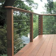 a wooden deck with metal railing and trees in the background