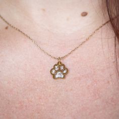 a close up of a woman's chest with a dog paw necklace on it