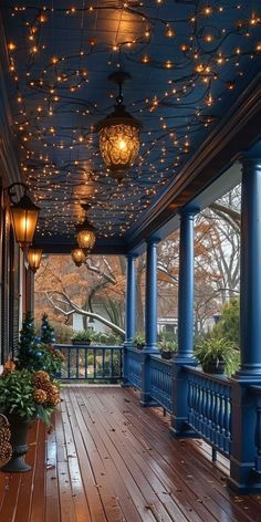 the porch is decorated with lights and potted plants on the wooden floor, along with hanging lanterns