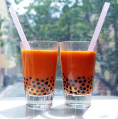 two glasses filled with orange juice sitting next to each other