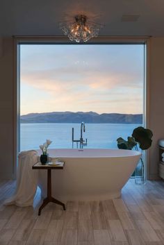 a bathroom with a large bathtub sitting next to a window overlooking the water and mountains