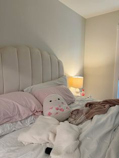 an unmade bed with pillows and blankets on it, next to a night stand