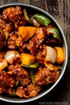 a bowl filled with meat and vegetables on top of a wooden table