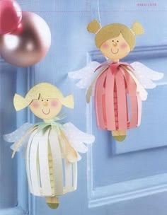 two paper angel ornaments hanging from a blue door