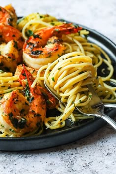 pasta with shrimp and spinach in a skillet on a marble counter top, ready to be eaten