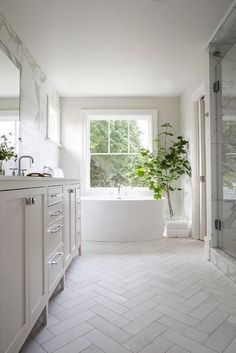 a bathroom with a tub, sink and large window next to the bathtub is decorated in white marble