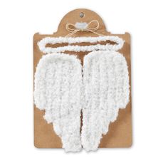 a card with two white angel wings attached to the front and back of it, on top of a piece of brown paper