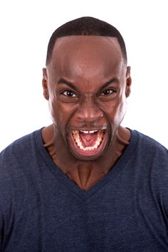 a man with his mouth open and an angry look on his face in front of the camera