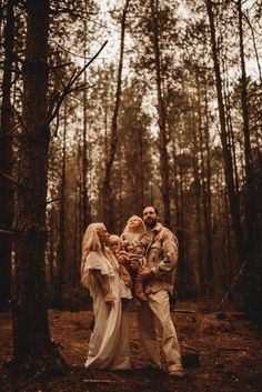 a man and woman standing next to each other in the woods