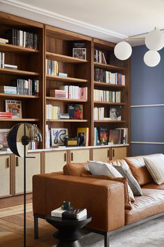 a living room filled with furniture and bookshelves next to a wall mounted book shelf