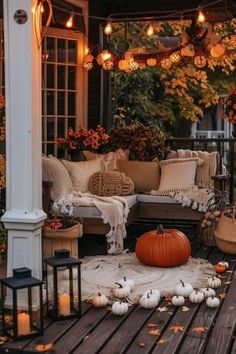 a porch decorated for fall with pumpkins and lanterns