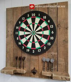 a dart board mounted to the side of a wooden wall next to some darts and spoons