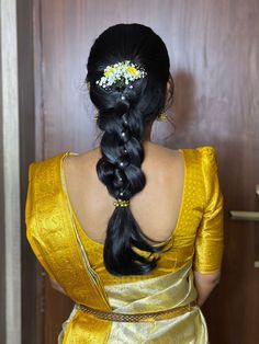 a woman with long black hair wearing a gold sari and flower in her hair