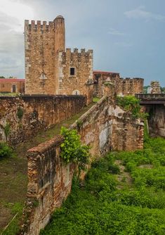 an old brick building sitting on top of a lush green field next to a bridge