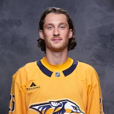 a young man in a hockey jersey posing for a photo with his head turned to the side